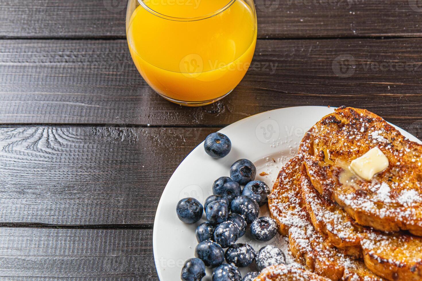 French toast on a white plate with blueberries and orange juice for breakfast photo
