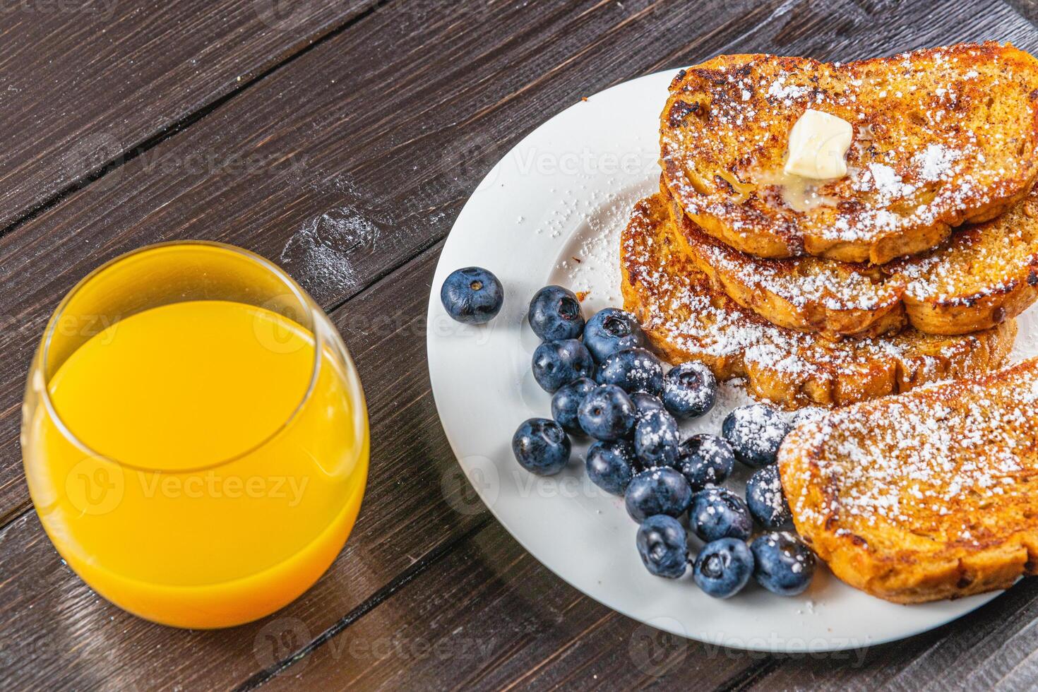 French toast on a white plate with blueberries and orange juice for breakfast photo