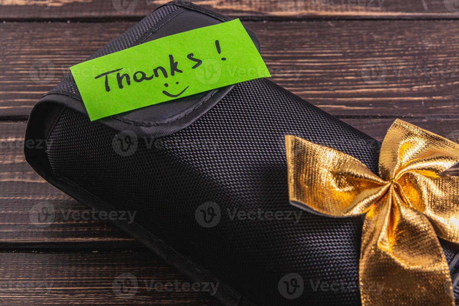 A black soft box with a green thank you label and a gold bow photo