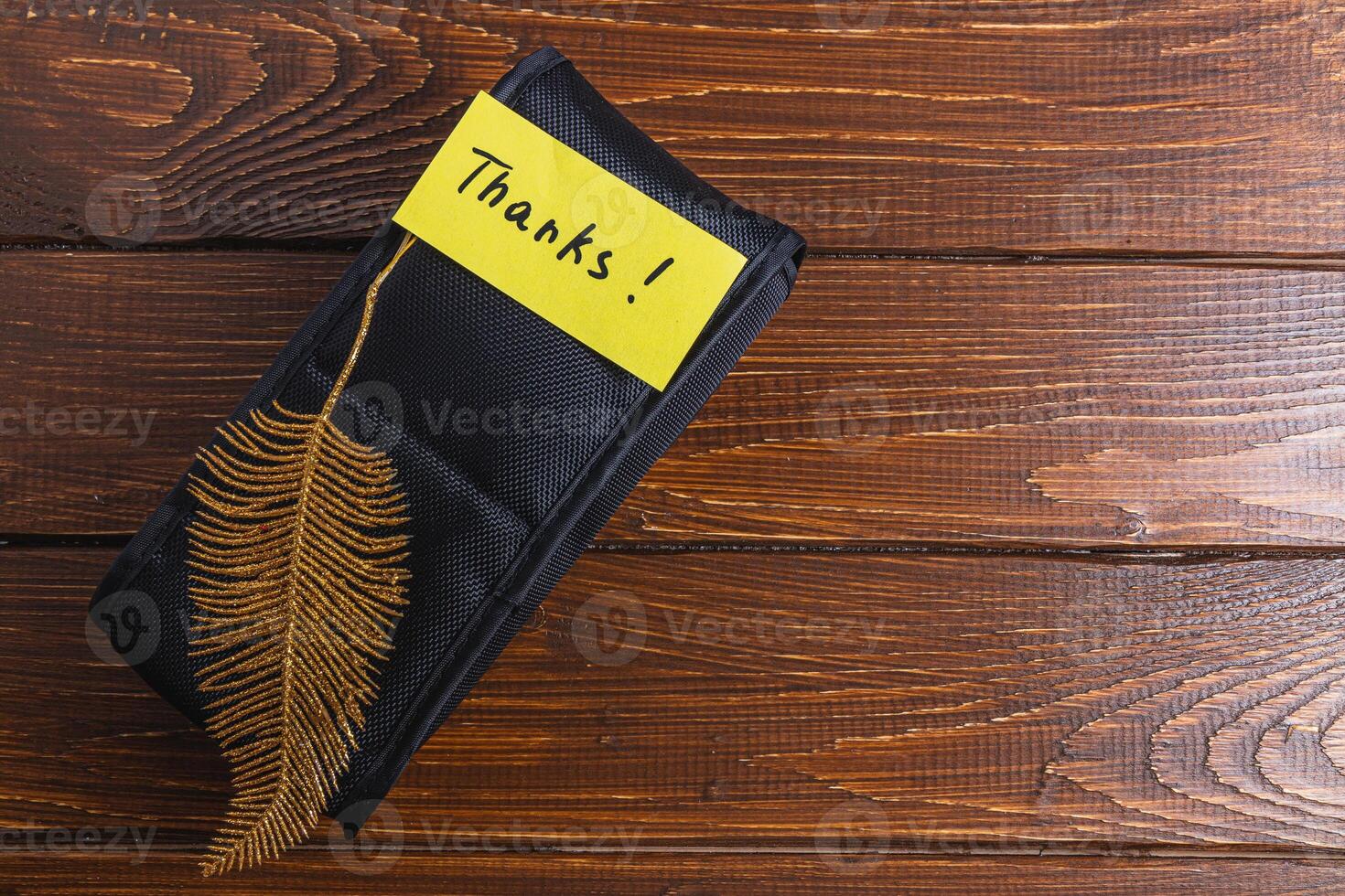 Black box on table with yellow thank you label and gold decorative leaf photo