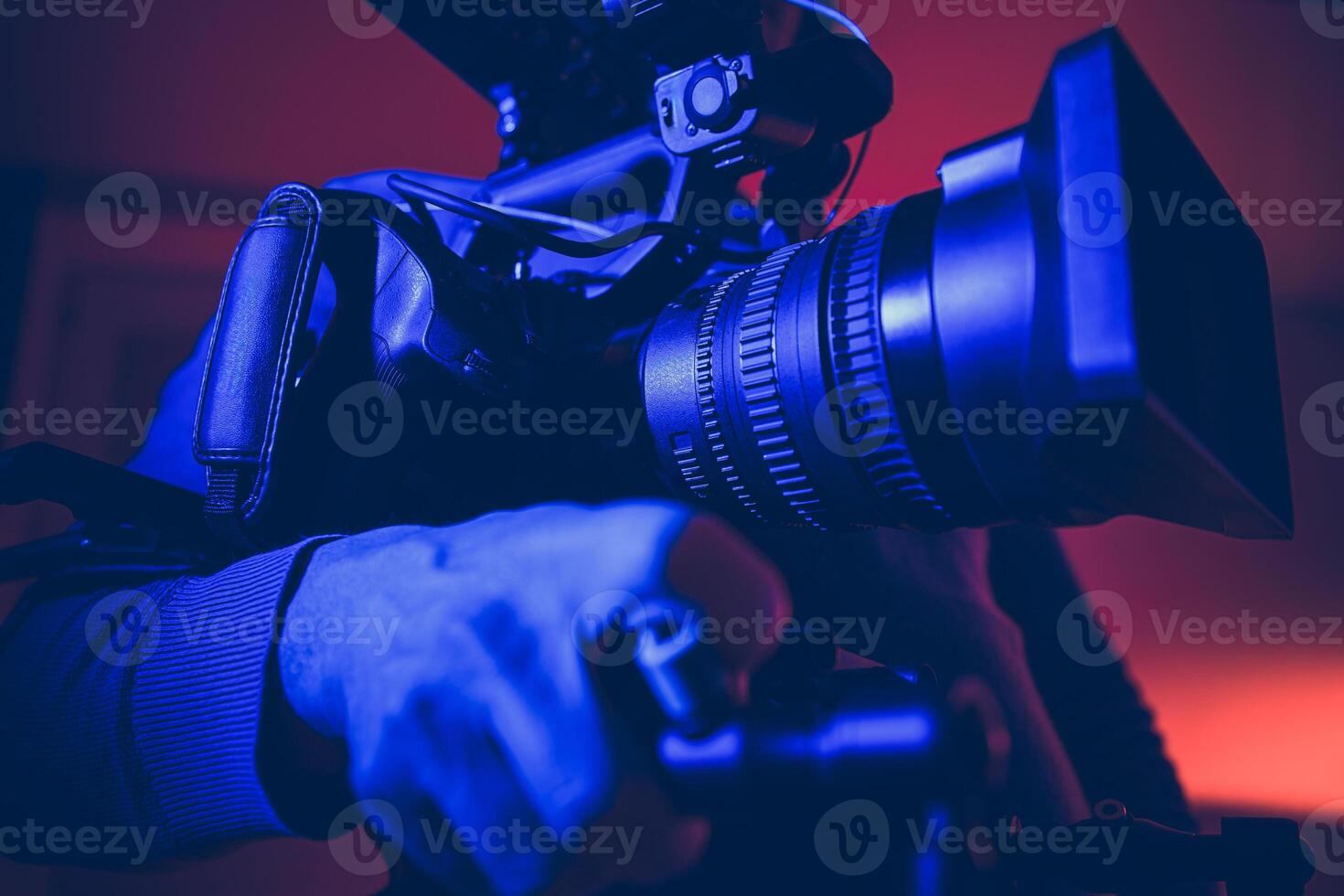 Professional Videographer Capturing a Moment With a Large Camera Under Colorful Lighting at Dusk photo