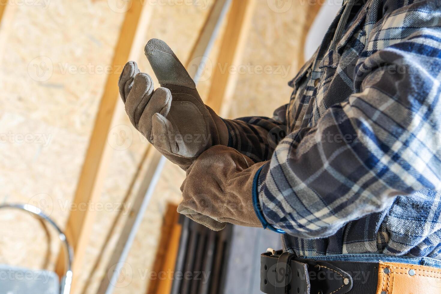 Worker Adjusts Gloves in a Workshop While Preparing for a Construction Task in the Morning Light photo
