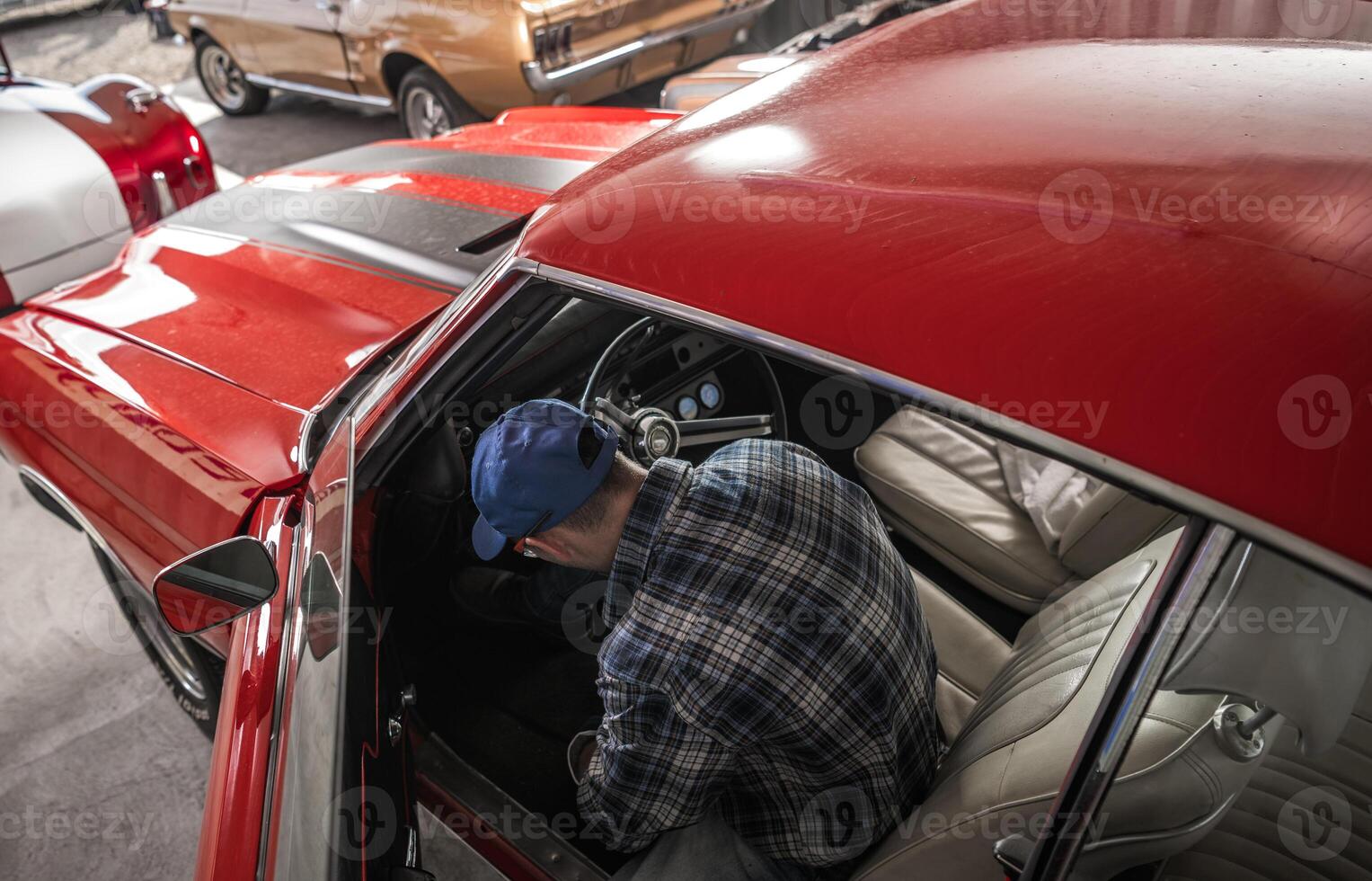 Man Working on a Classic Red Car Inside a Vintage Automobile Collection Garage photo