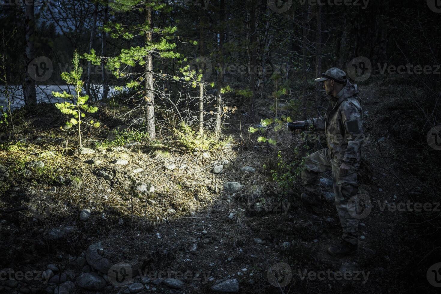 A Person Exploring a Forested Area With a Flashlight During Nighttime in a Remote Location photo