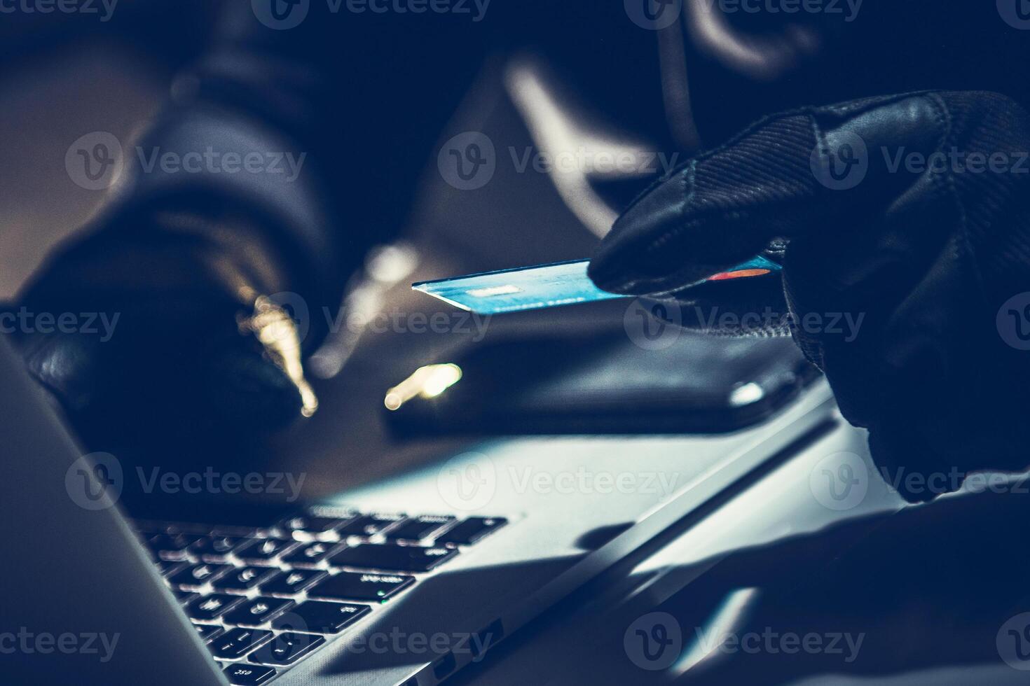 Criminal Using a Computer to Commit Fraud With a Credit Card at Night in a Dimly Lit Room photo