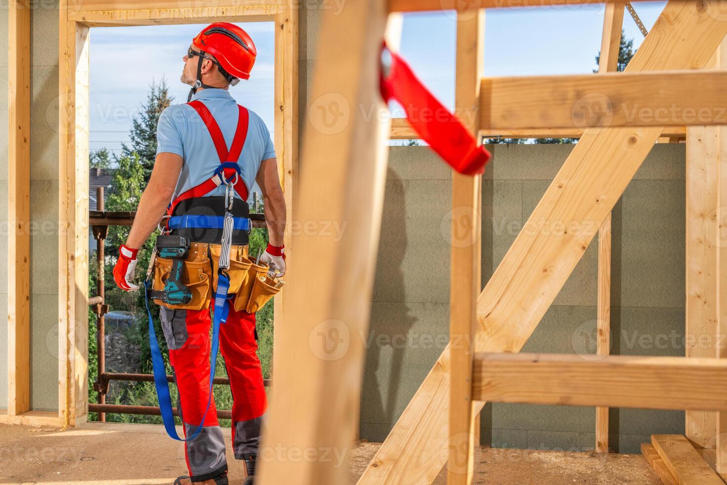 Construction Worker Assessing a Wooden Frame Structure Under a Clear Sky During the Day photo