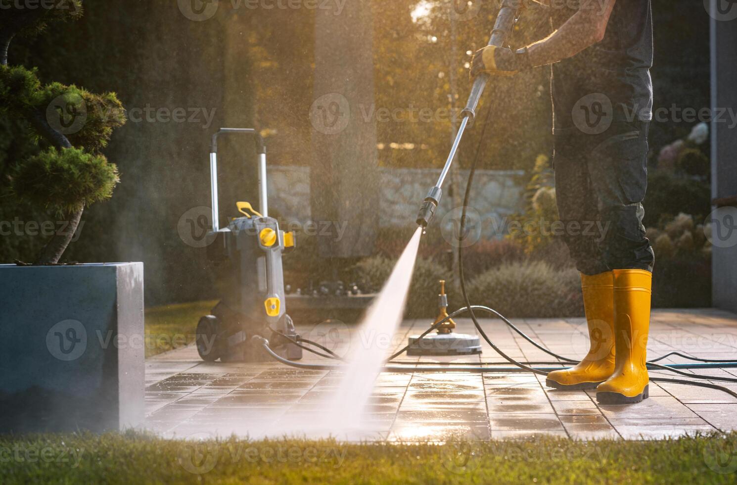 A Person Power Washing a Patio With a Pressure Washer in a Sunny Outdoor Setting photo