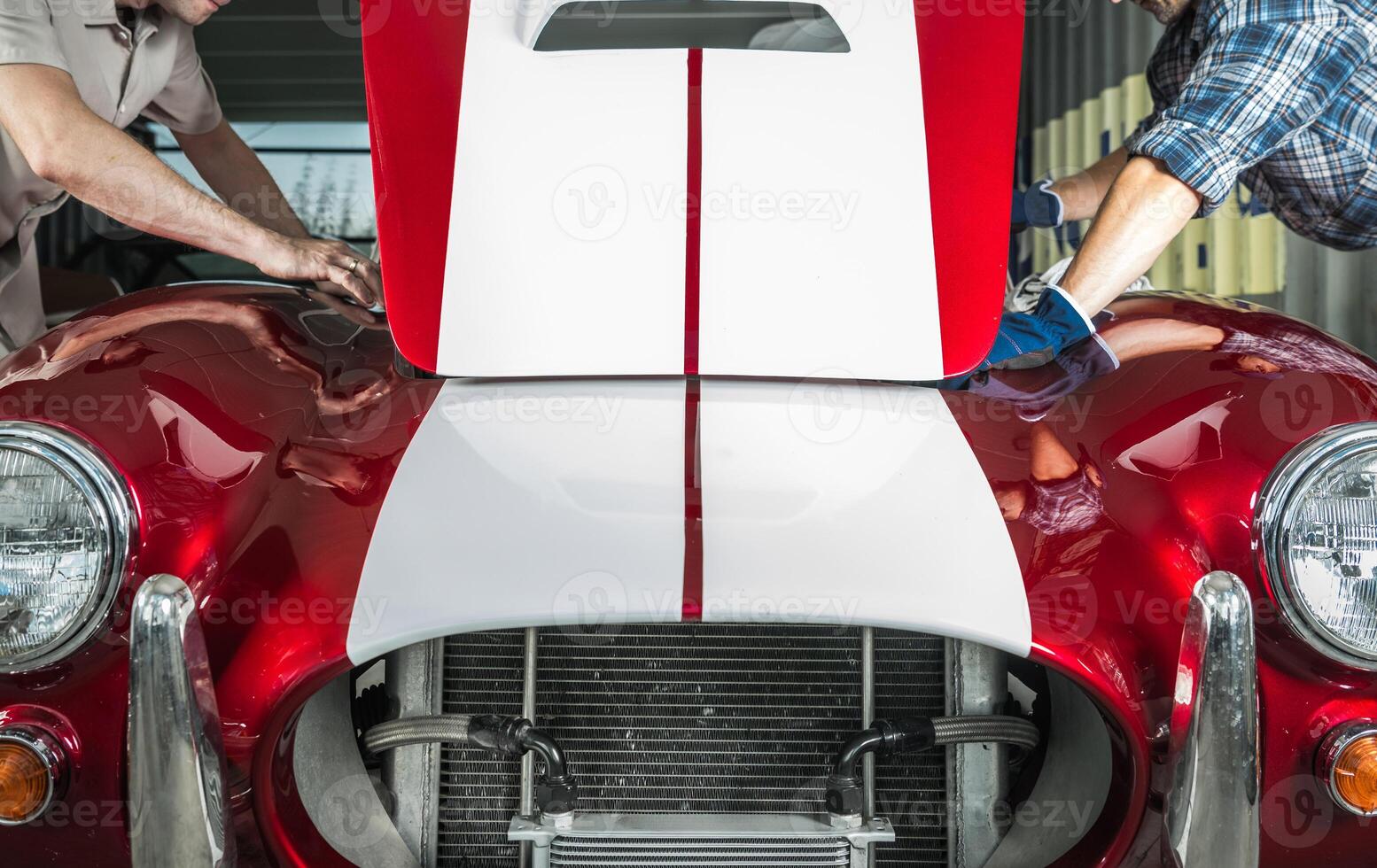 Car Enthusiasts Inspecting a Classic Red Sports Car in a Garage During Daylight Hours photo