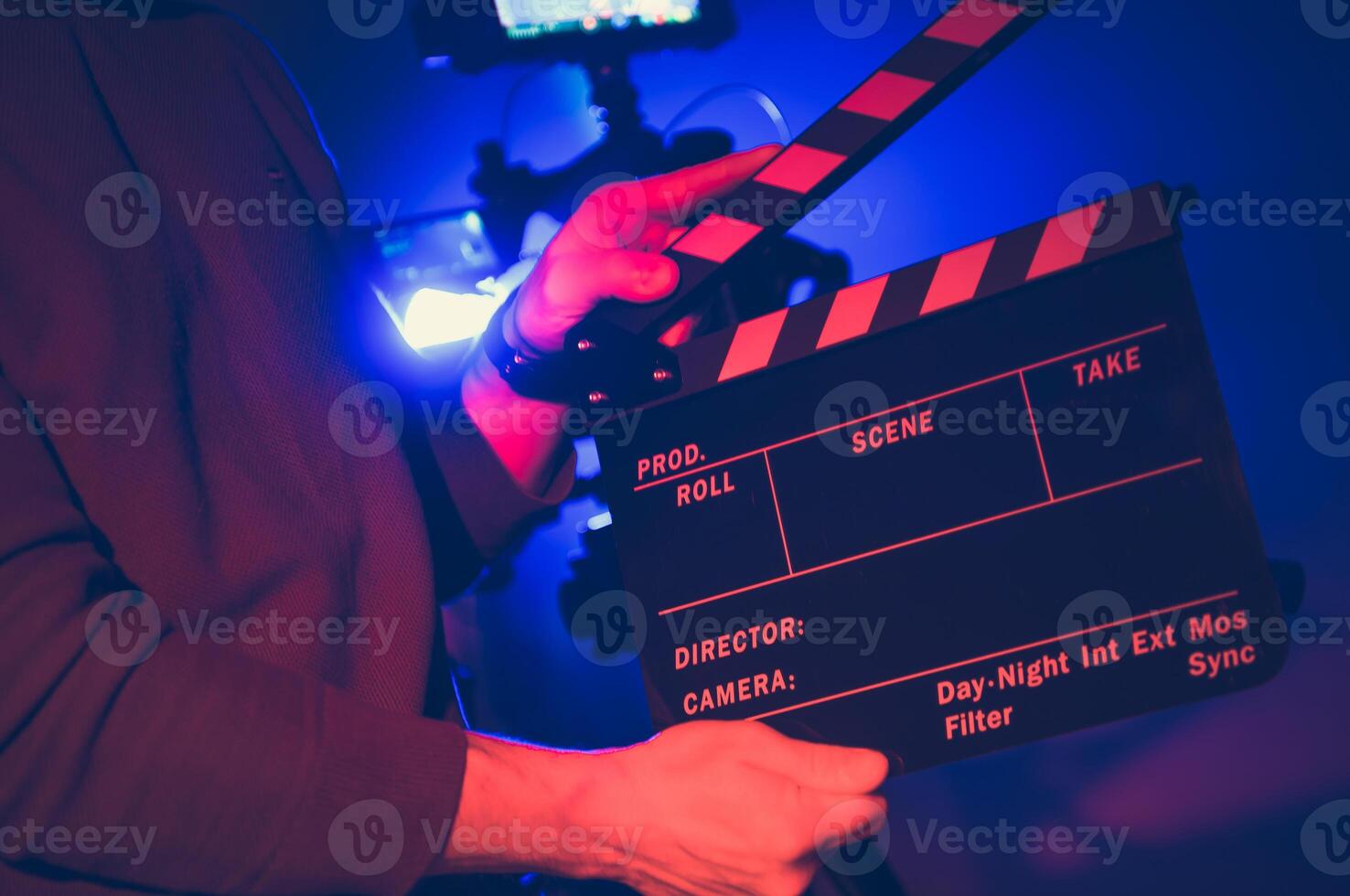 A Filmmaker Prepares a Clapperboard for a Nighttime Shoot Indoors With Colorful Lighting Effects photo