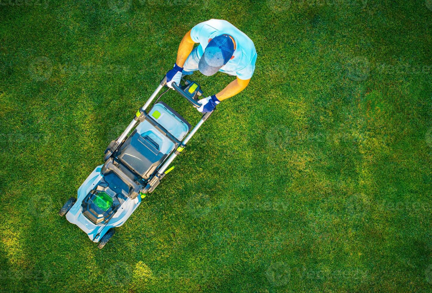 A Person Mows a Lush Green Lawn With a Modern Mower on a Sunny Day in a Residential Area photo