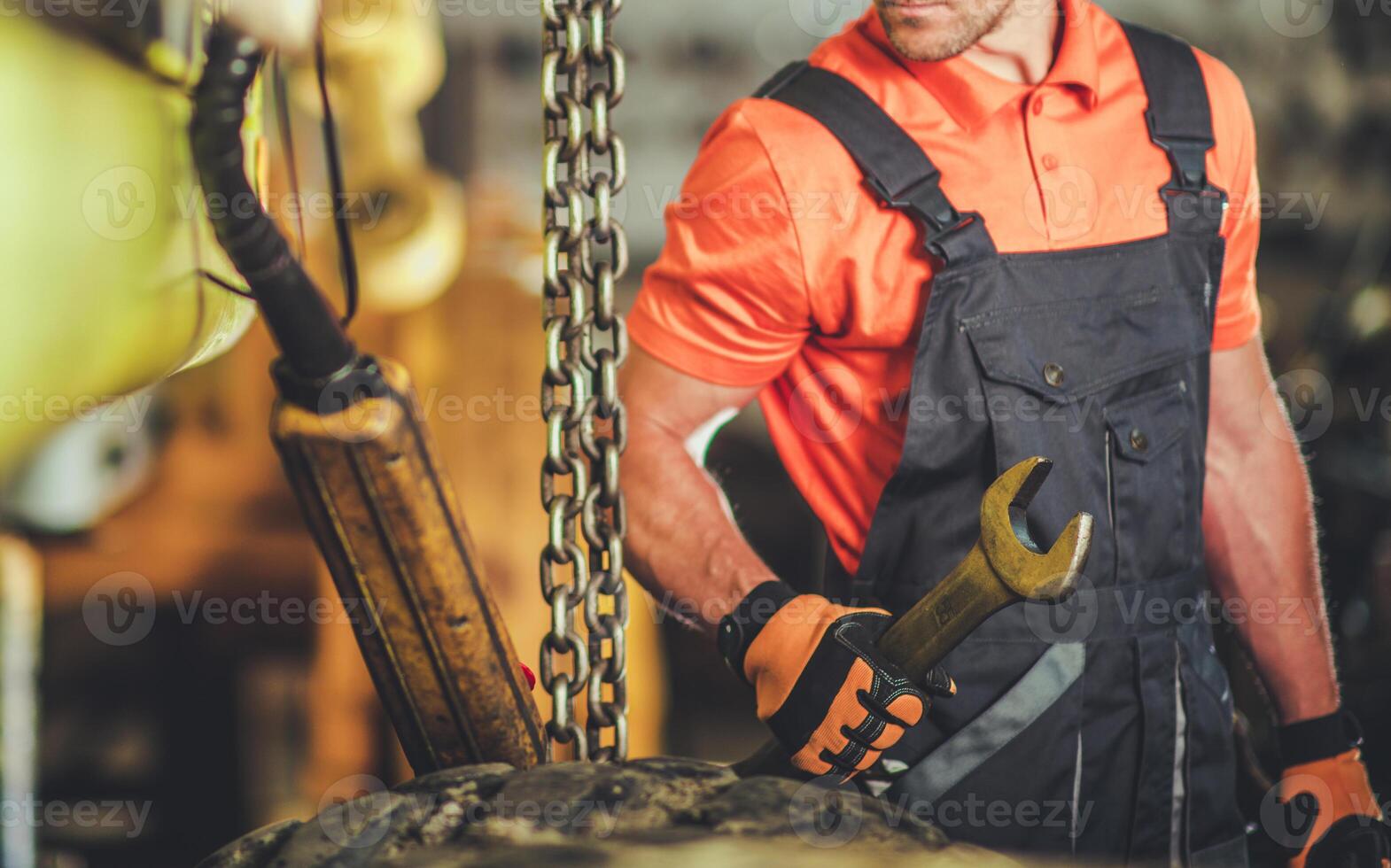 Skilled Worker Using a Wrench While Repairing Heavy Machinery in a Workshop Setting photo