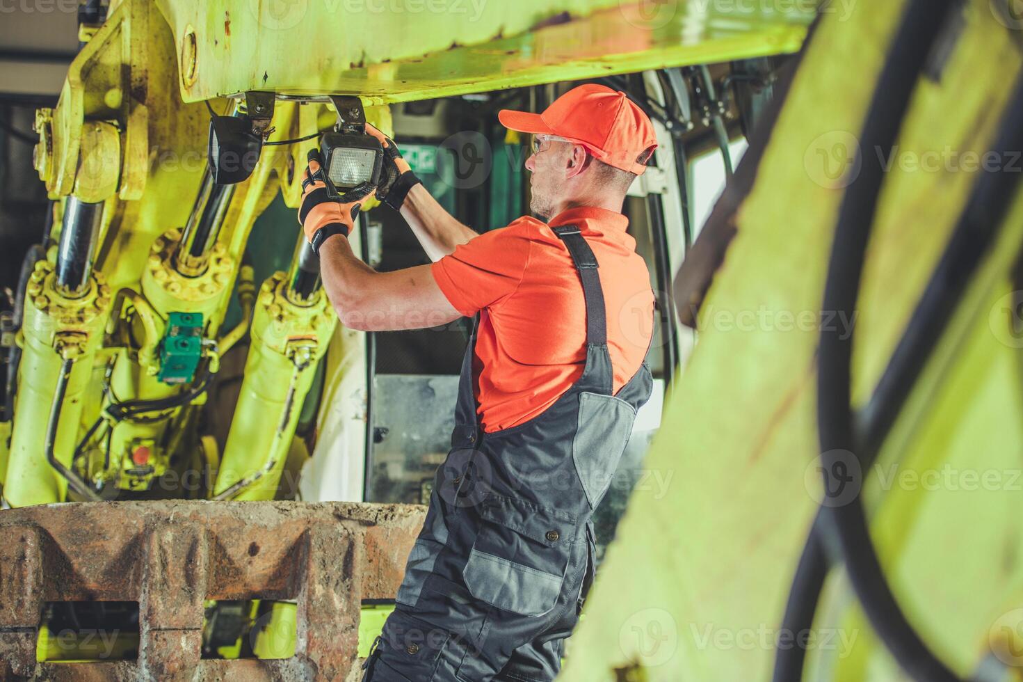 Worker Conducting Maintenance on Heavy Machinery in an Industrial Setting During Daylight Hours photo