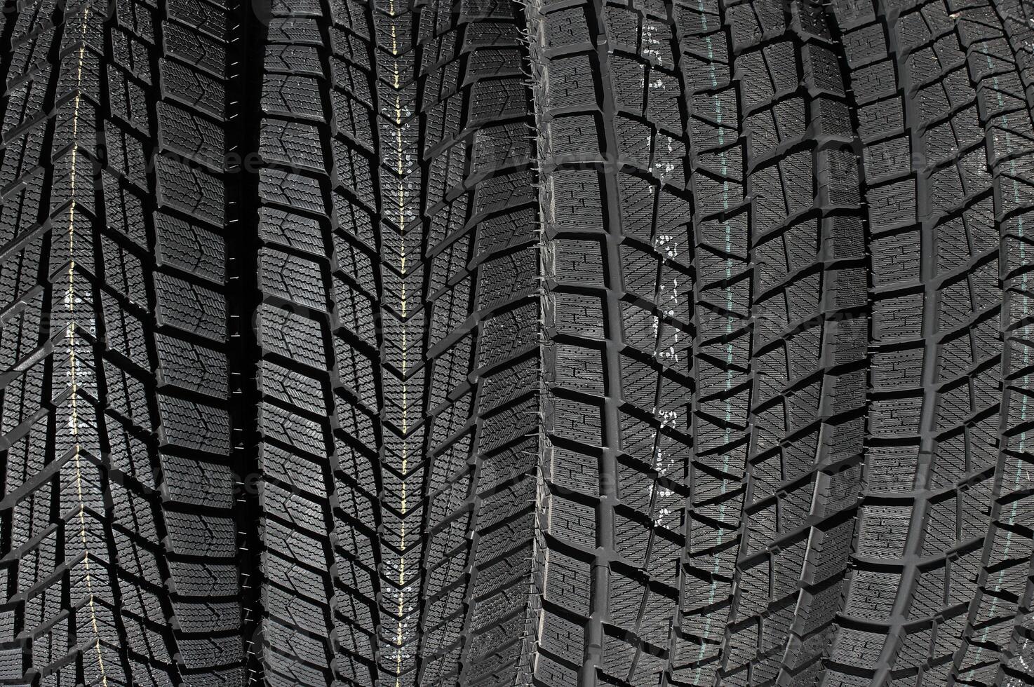 Closeup image of textured pattern of directional tread blocks and large sipes on winter non studded tires photo
