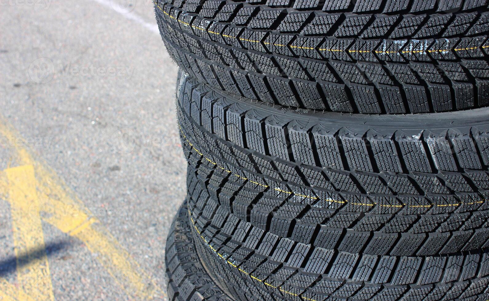 A set of four new winter tires are stacked on asphalt before the seasonal tire change. Same tread pattern tires detailed image photo