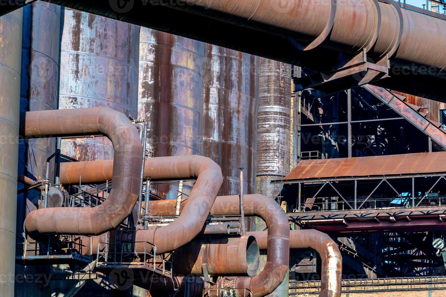 Rusty industrial pipes winding through factory exterior photo