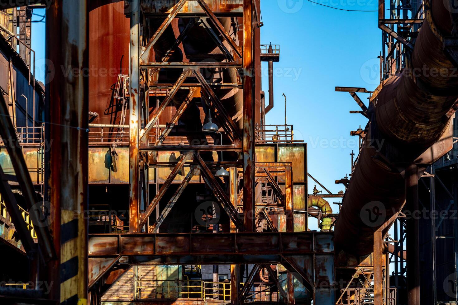 Rusty industrial structure with pipes and metal beams in an abandoned factory photo
