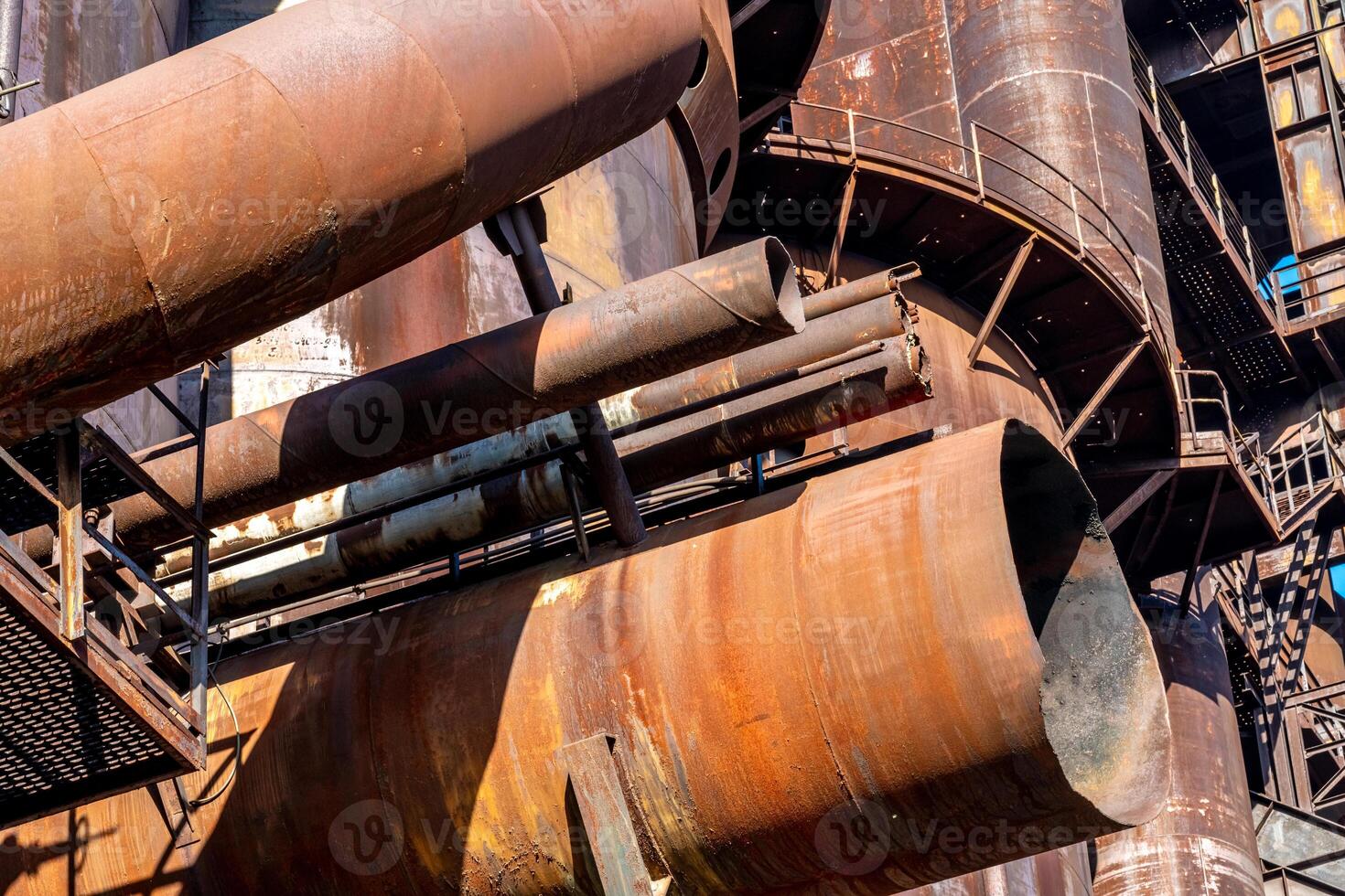 Rusty industrial pipes forming abstract shapes in the sunlight photo