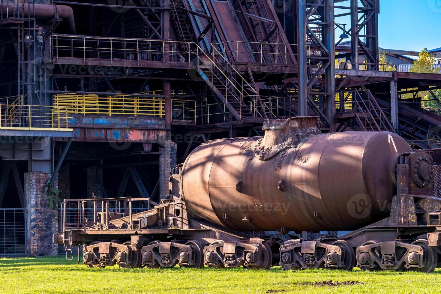 Old rusty ladle wagon standing in front of industrial building photo
