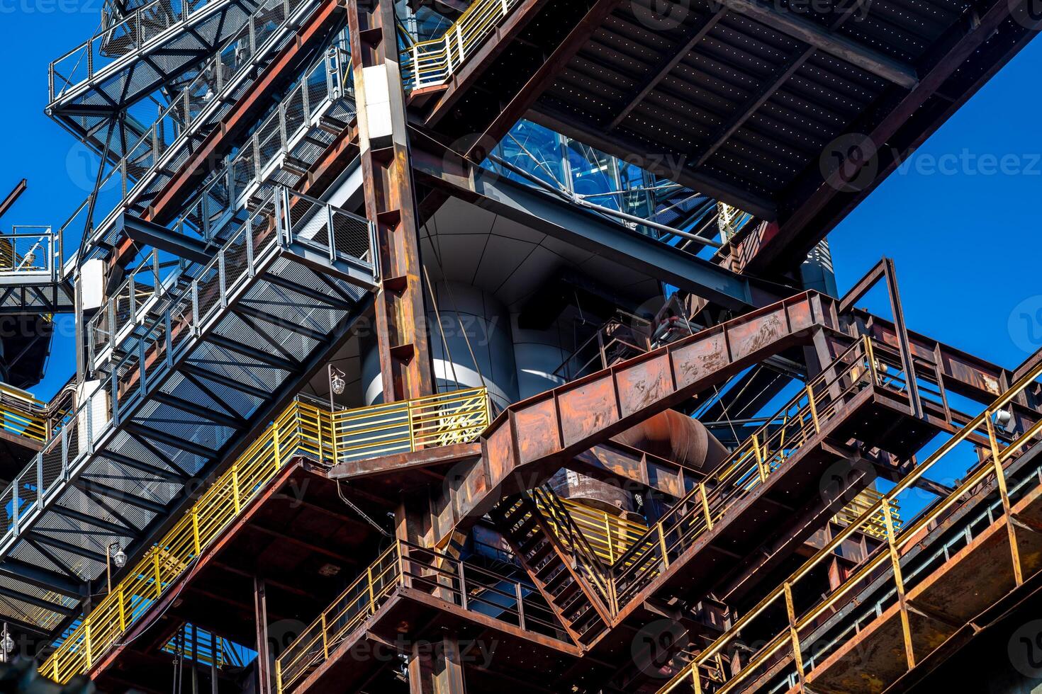 Rusty industrial building showing weathered metal structures under blue sky photo