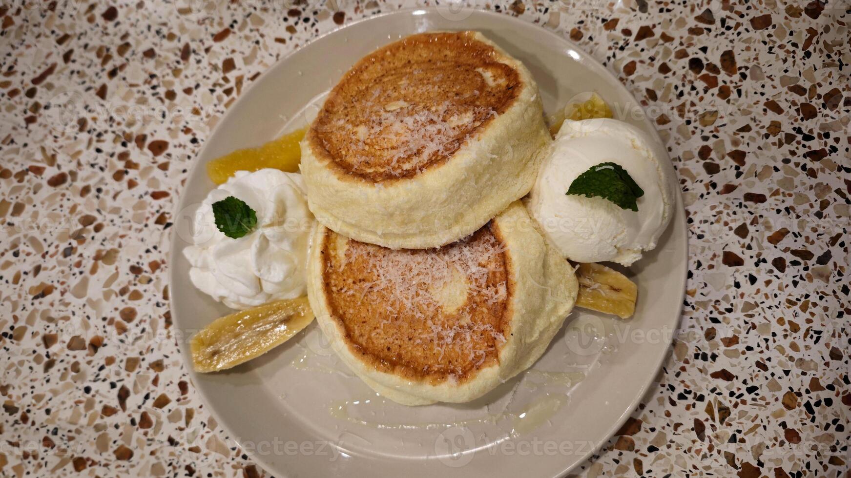 Delicious Japanese Fluffy Pancakes with Vanilla Ice Cream and Fresh Banana Slices on a Terrazzo Table photo