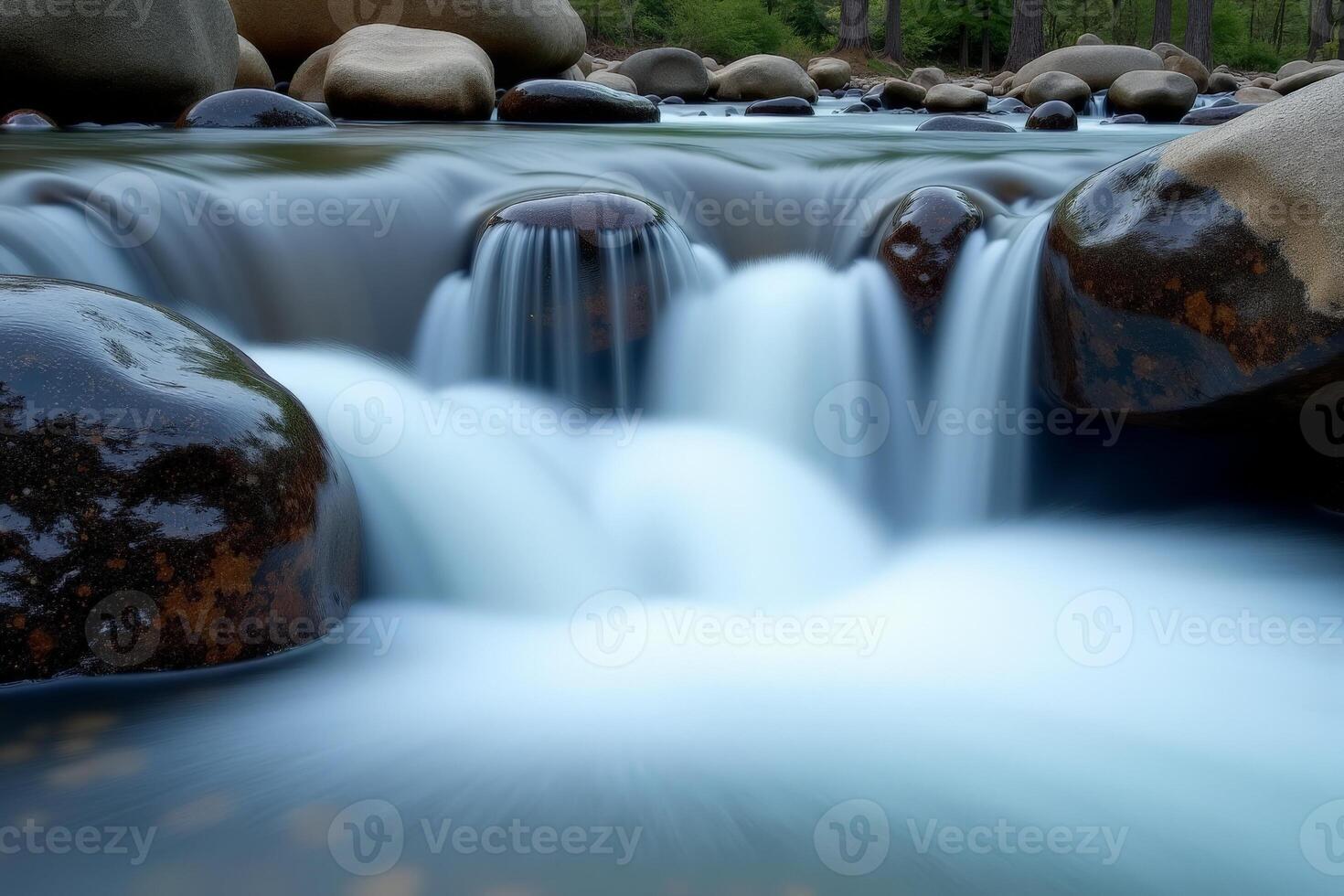 A stream of water flows over rocks in a forest photo
