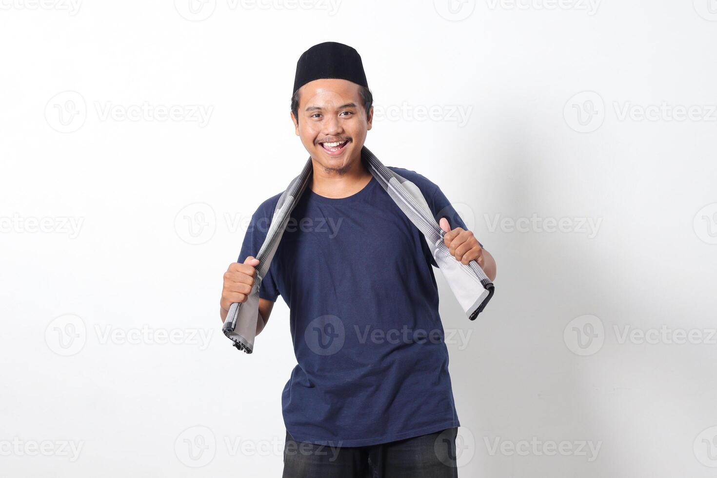 Portrait of confident Asian muslim man wearing scarf and skullcap standing with cool pose and holding his sarung. Isolated image on white background photo