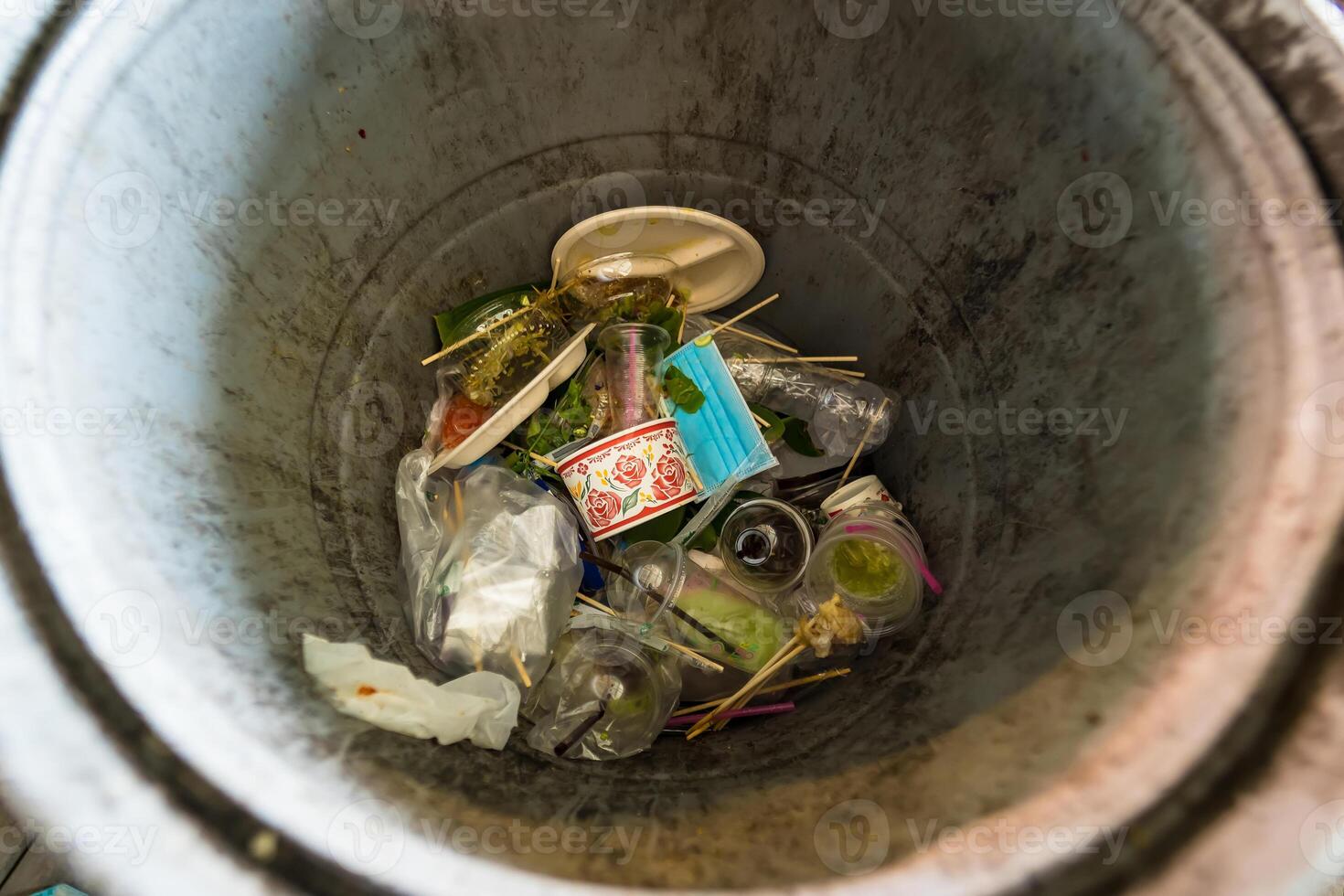 Overflowing Trash Bin with Food Containers and Plastic Items photo
