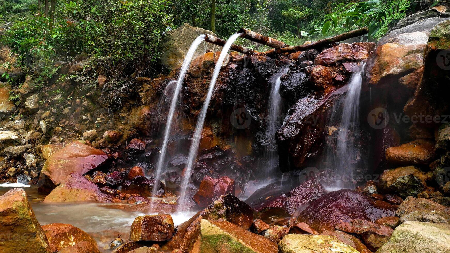 A hot spring flowing from bamboo is located in the middle of the forest of Mount Halimun Salak National Park, Bogor, Indonesia. The hot water comes from the active Mount Salak Crater. photo