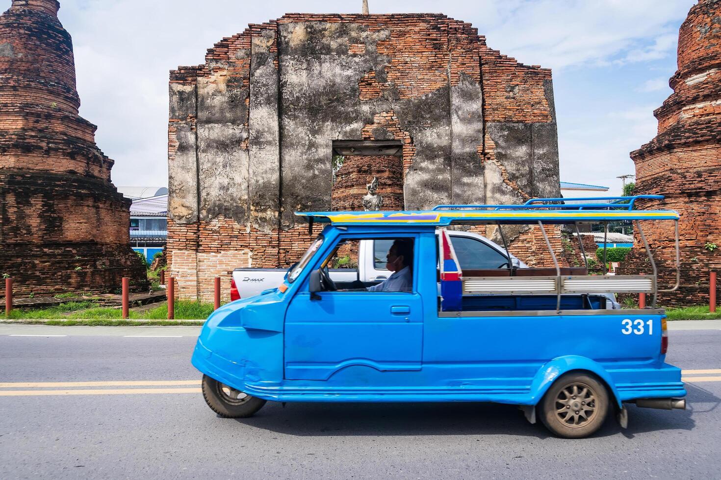 Ayutthaya, Thailand - April, 26, 2024 Tuk-Tuk Driving Past Historical Landmarks at Ayutthaya, Thailand. photo