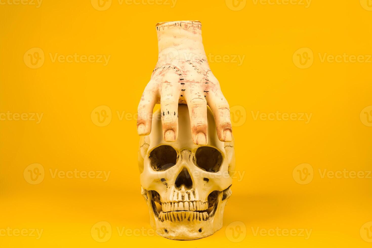 Severed Hand on a Skull Against a Yellow Background.Artistic and Spooky Halloween-Themed Display photo