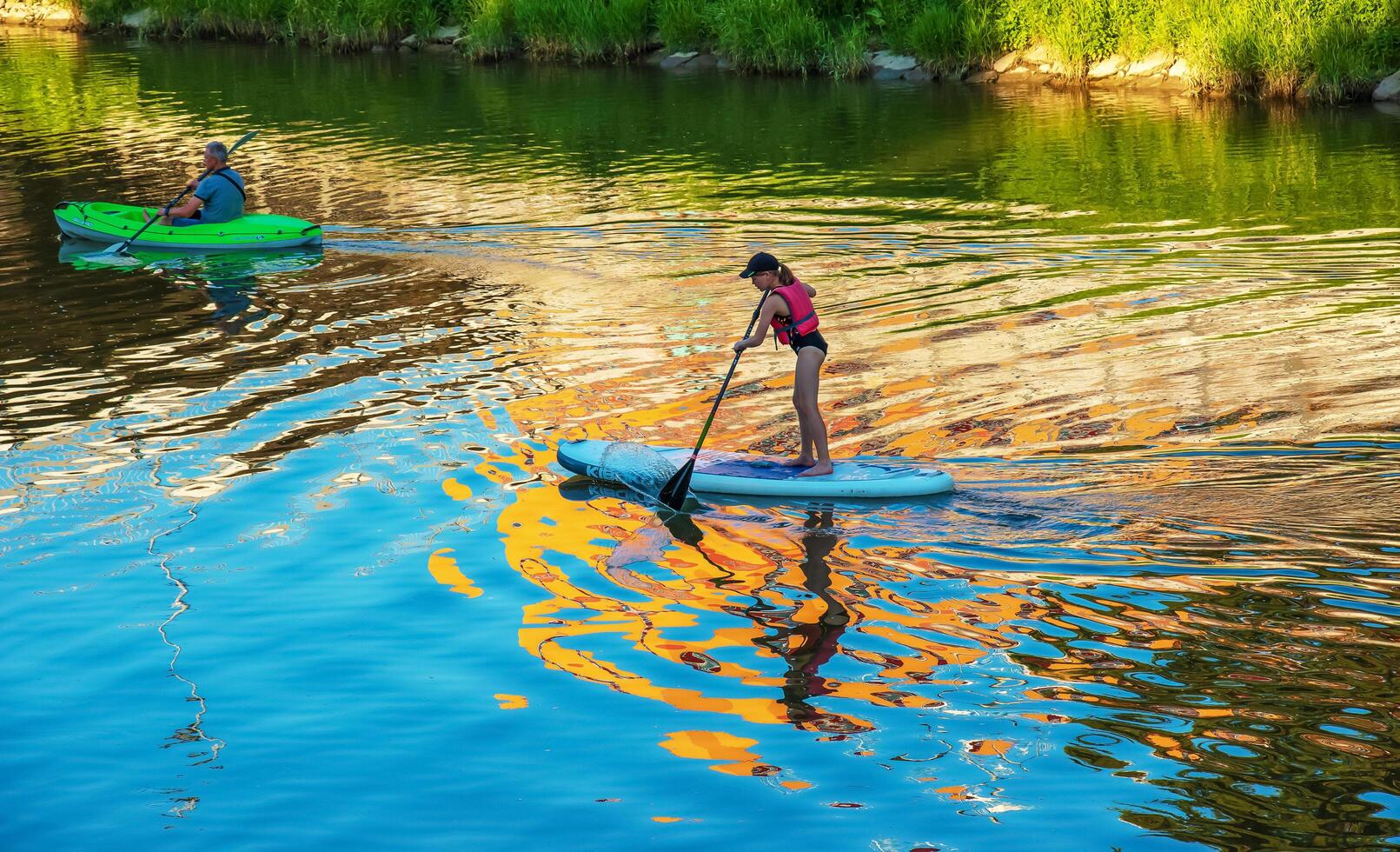 Nitra, Slovakia - 06.15.2022 A young girl and a middle-aged man are sailing in different canoes on the Nitra river. photo