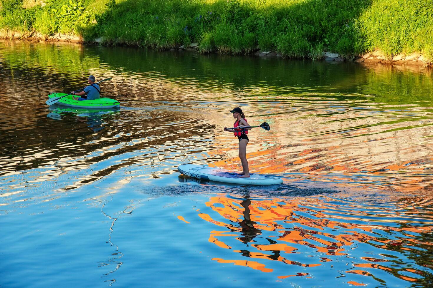 Nitra, Slovakia - 06.15.2022 A young girl and a middle-aged man are sailing in different canoes on the Nitra river. photo
