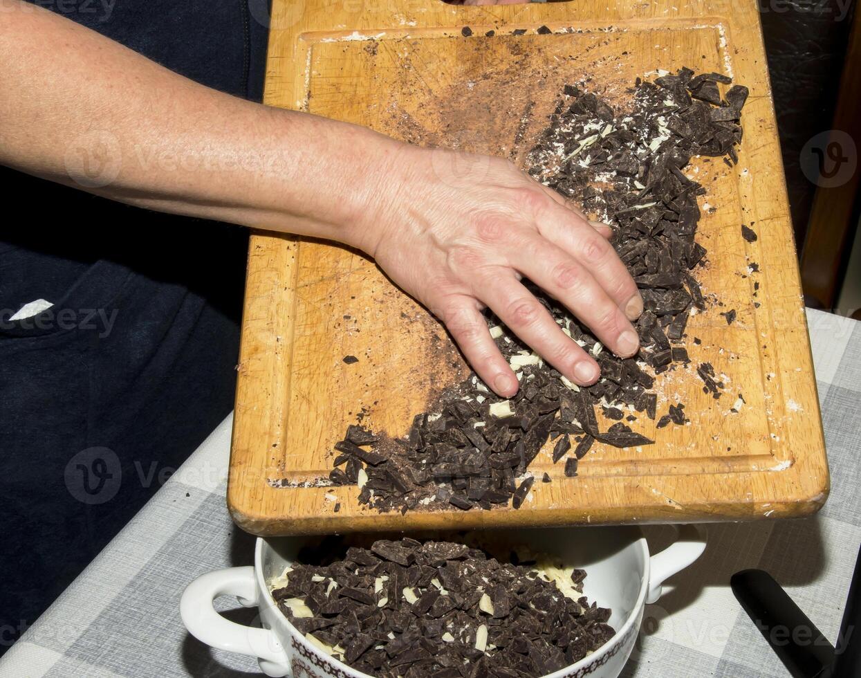 The hands of the cook pour the crushed cocoa butter and grated cocoa into a container for making chocolate. photo