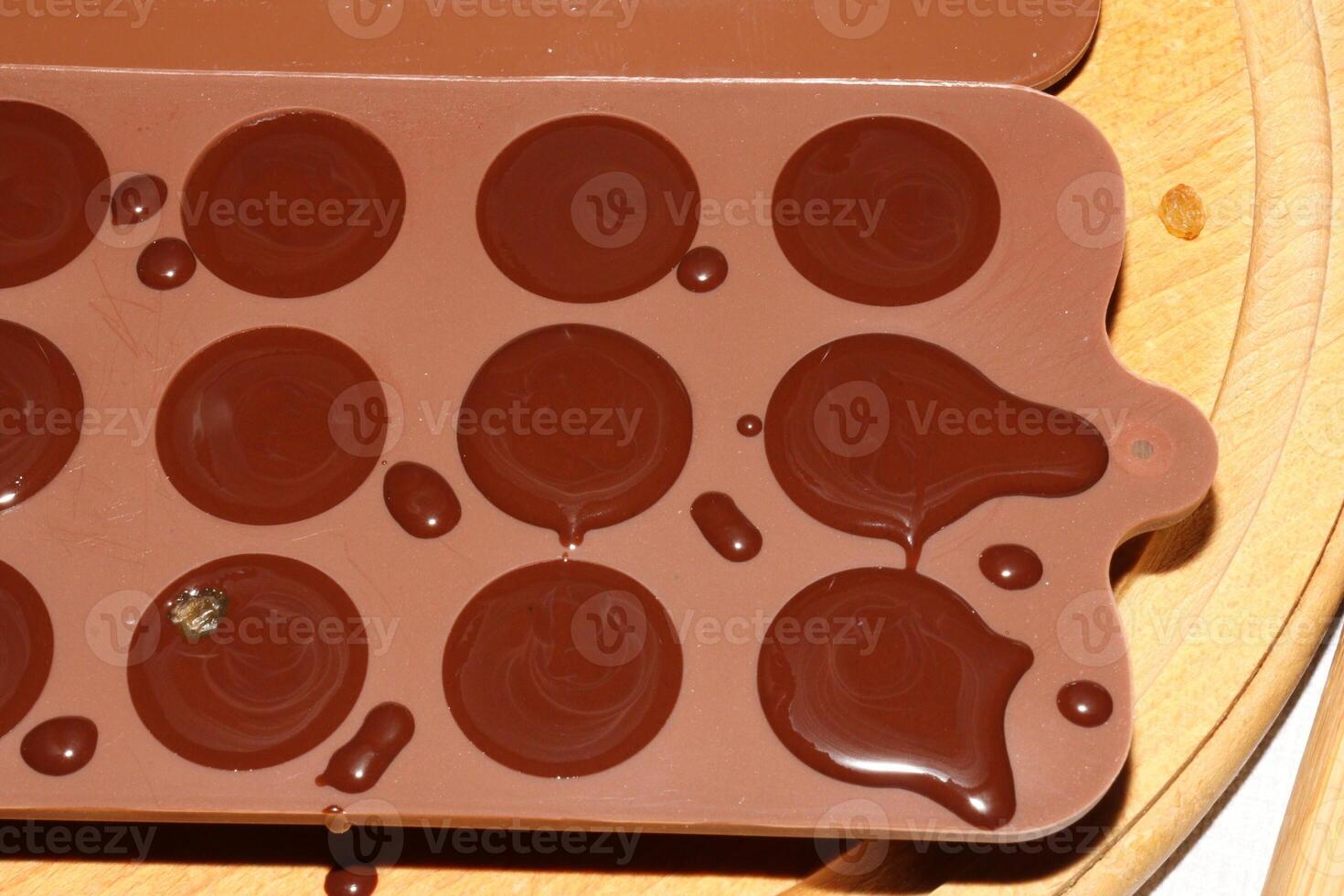 Silicone molds for shaping chocolate and sweets are filled with hot chocolate to cool. photo