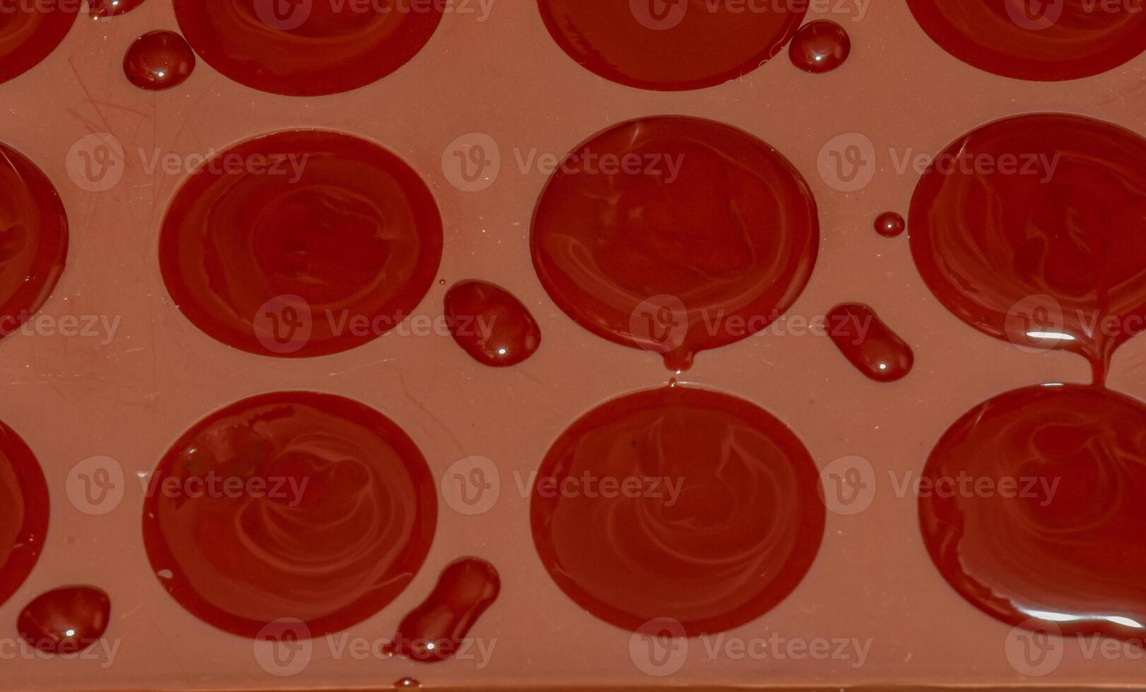 Silicone molds for shaping chocolate and sweets are filled with hot chocolate to cool. photo