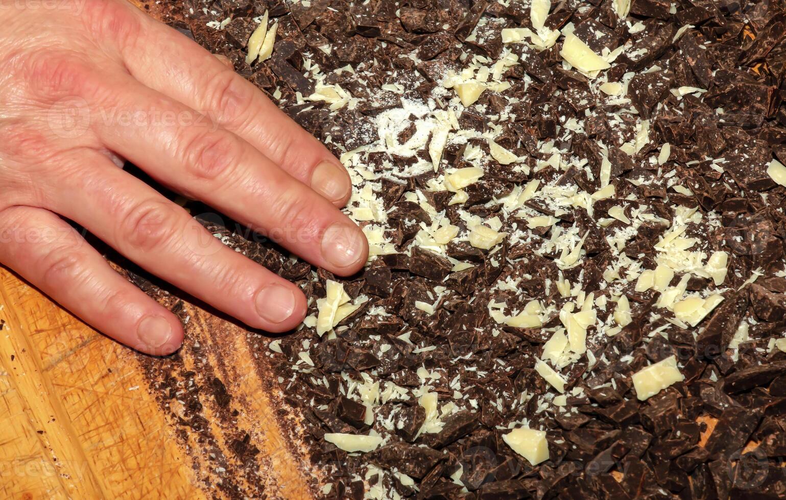 The hands of the cook pour the crushed cocoa butter and grated cocoa into a container for making chocolate. photo
