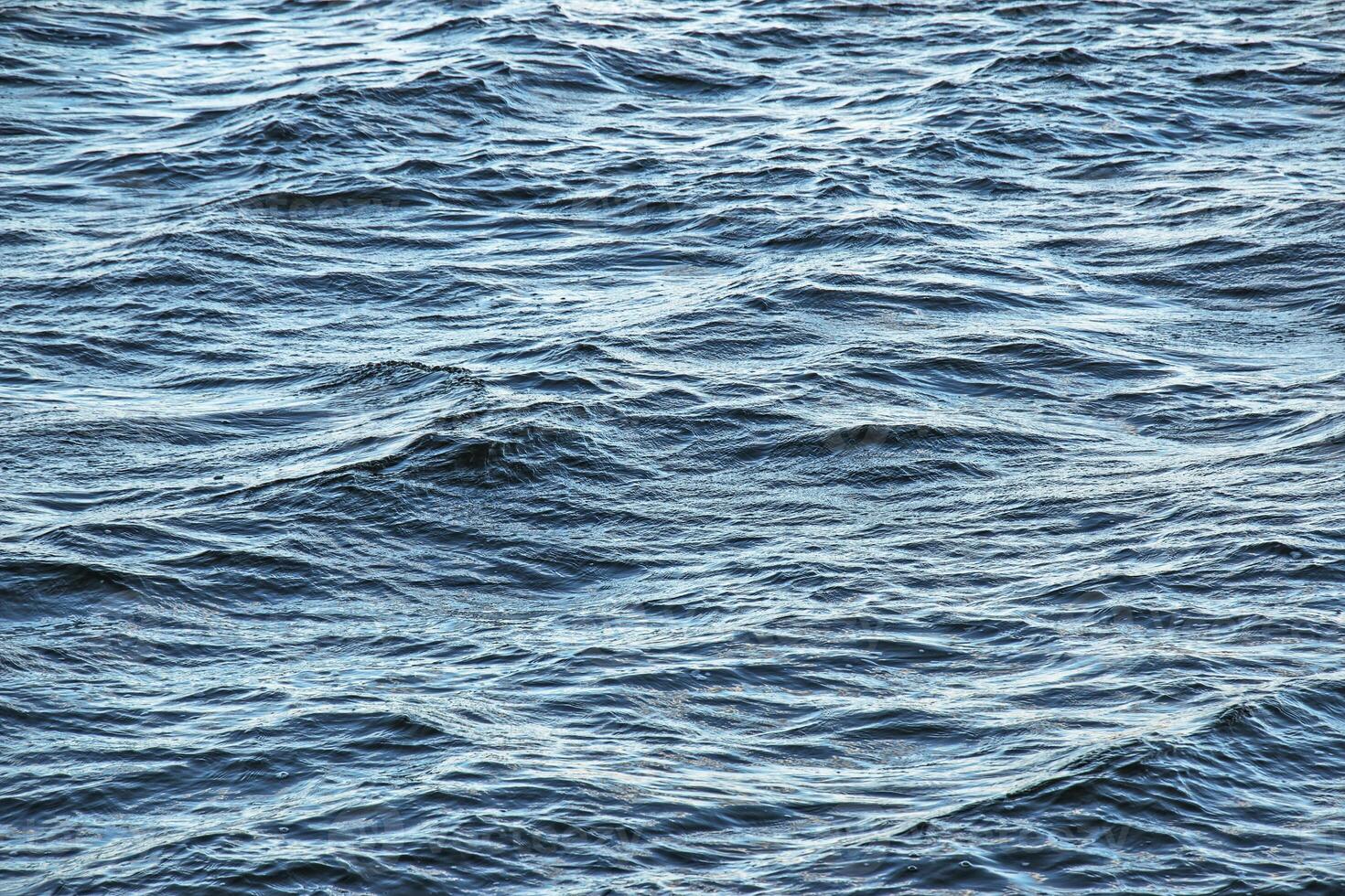 The background of the surface of the water of the river with small ripples and reflections of autumn colors. photo