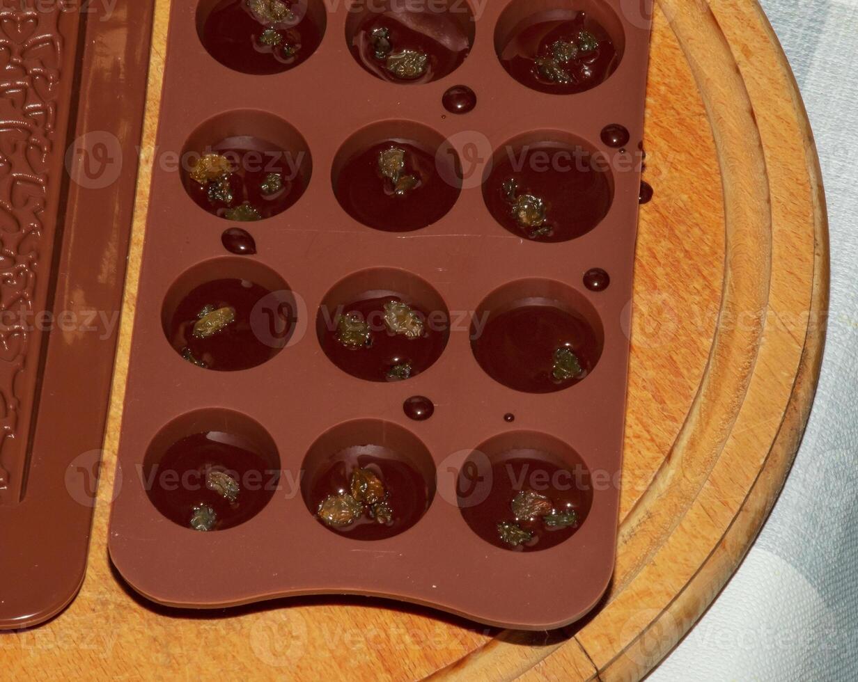 Silicone molds for shaping chocolate and sweets are filled with hot chocolate to cool. photo