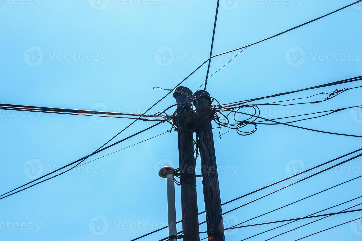Electric pole power lines outgoing electric wires againts on cloud blue sky. photo