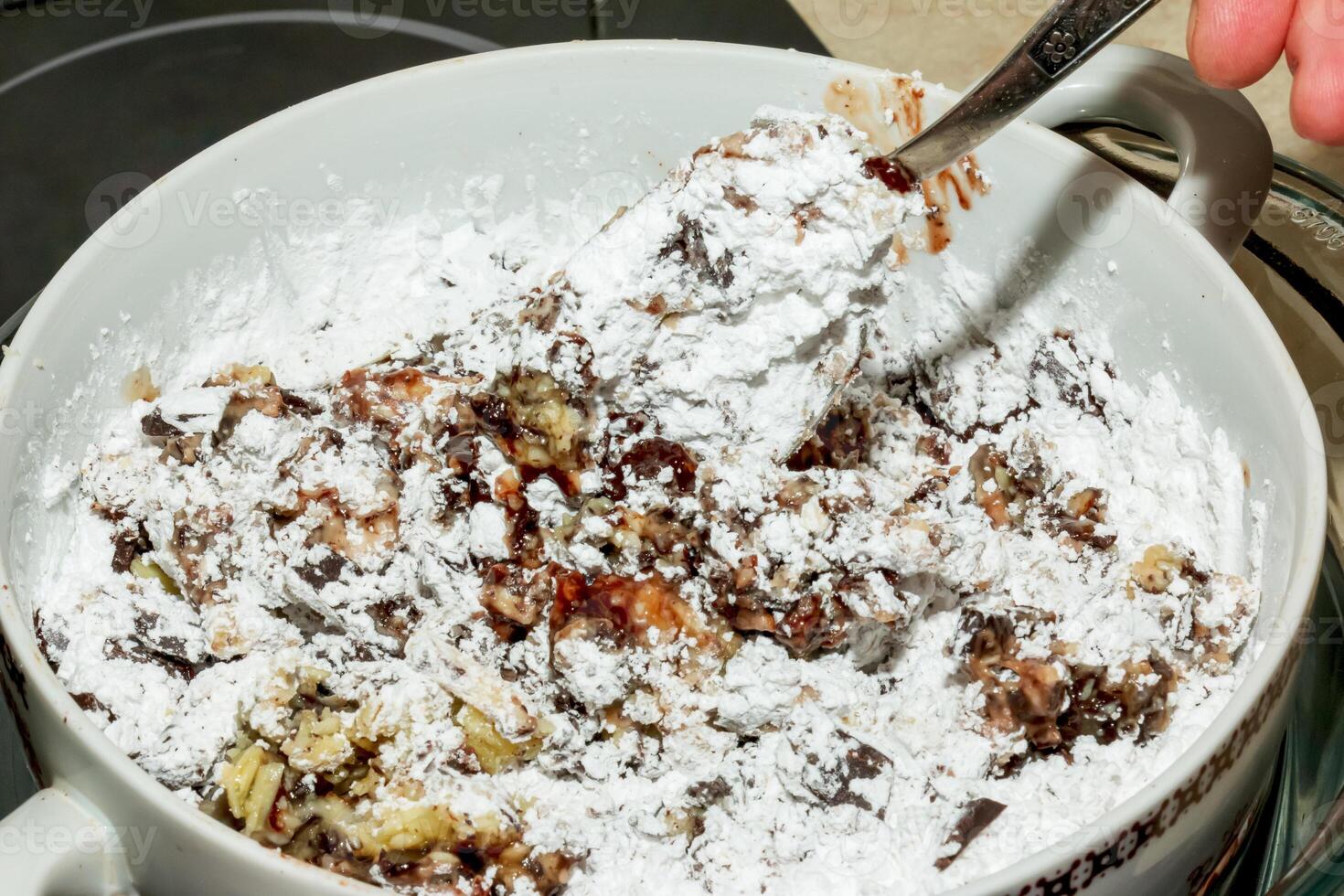 Powdered sugar, cocoa butter and grated cocoa in a container for making chocolate are heated in a water bath. photo