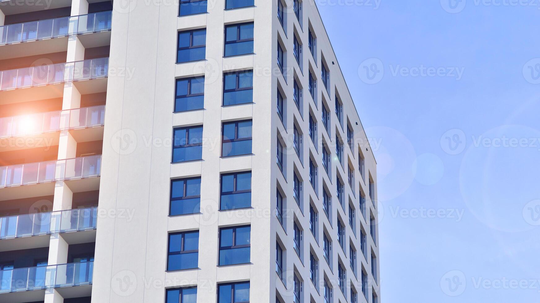Modern high-rise apartment building in white, stand tall against a blue sky, exemplifying innovative urban architecture with sleek, angular designs. photo