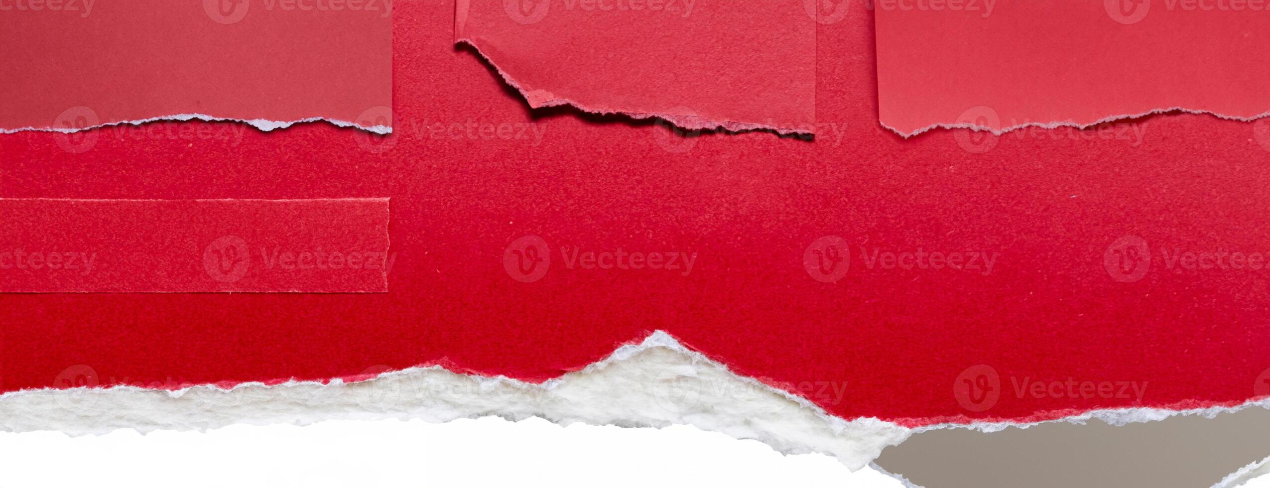 Close-up of a torn red paper edge on a white background, showing a rough texture and contrasting colors. photo