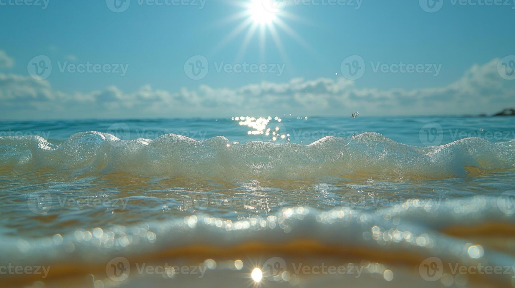 Waves roll softly against the sand, sparkling under the bright midday sun photo