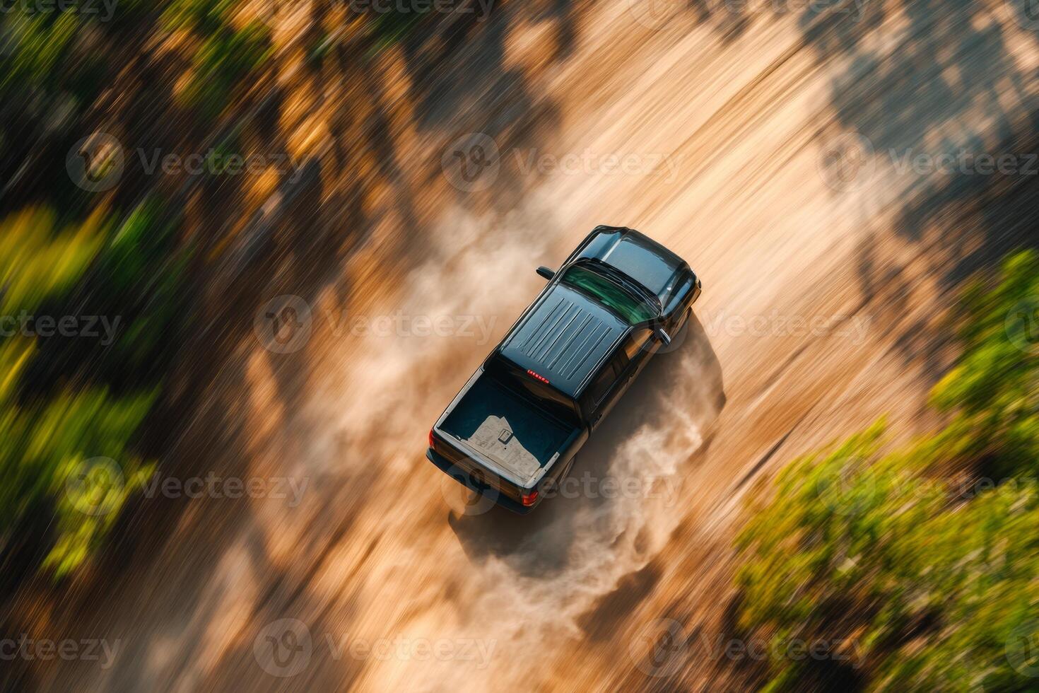 A sleek black pickup truck drives along a winding dirt road in a lush green forest, creating clouds of dust that enhance the serene scenery, inviting adventure and exploration in nature photo