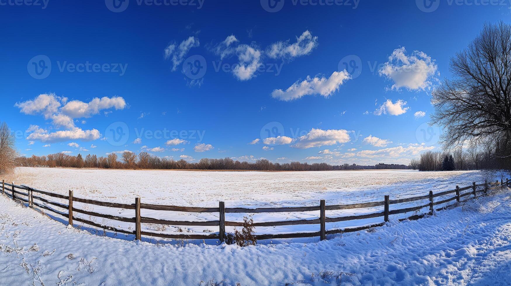A serene winter scene shows a snowcovered wooden fence leading into a vast snowy field under a bright blue sky, creating an ideal tranquil setting for winterthemed visuals of peace photo