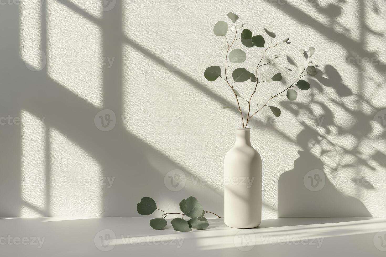 This serene setting showcases a minimalist design with a white vase of eucalyptus leaves, casting delicate shadows on a beige backdrop, ideal for branding and promoting calm in living spaces photo