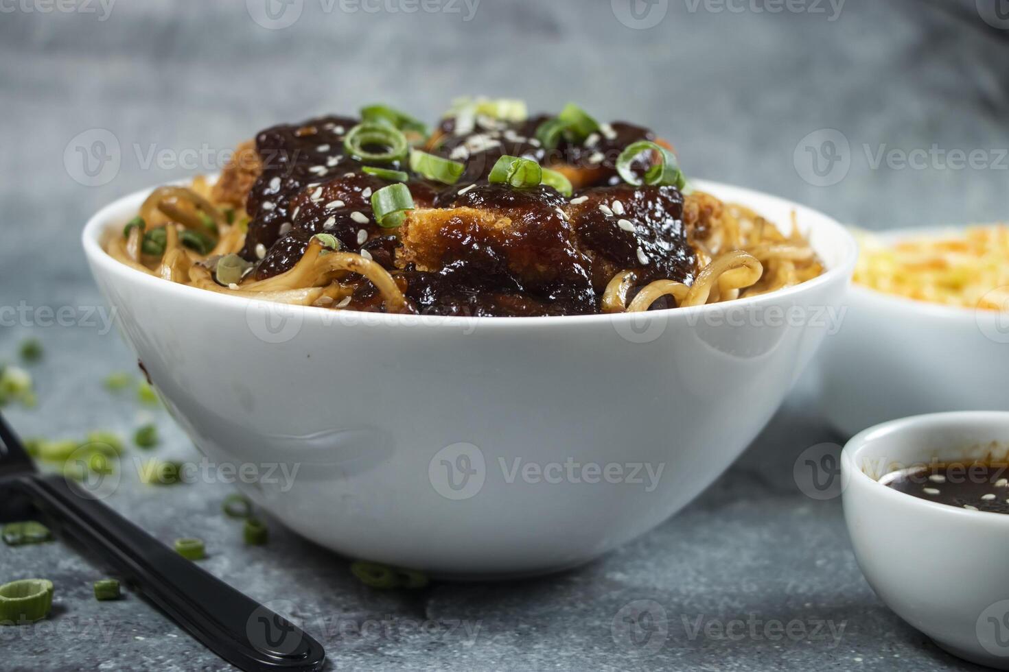 Teriyaki Fried Chicken Noodles with green onion, spicy sauce, cabbage salad and fork served in bowl isolated on grey background side view of japanese food photo