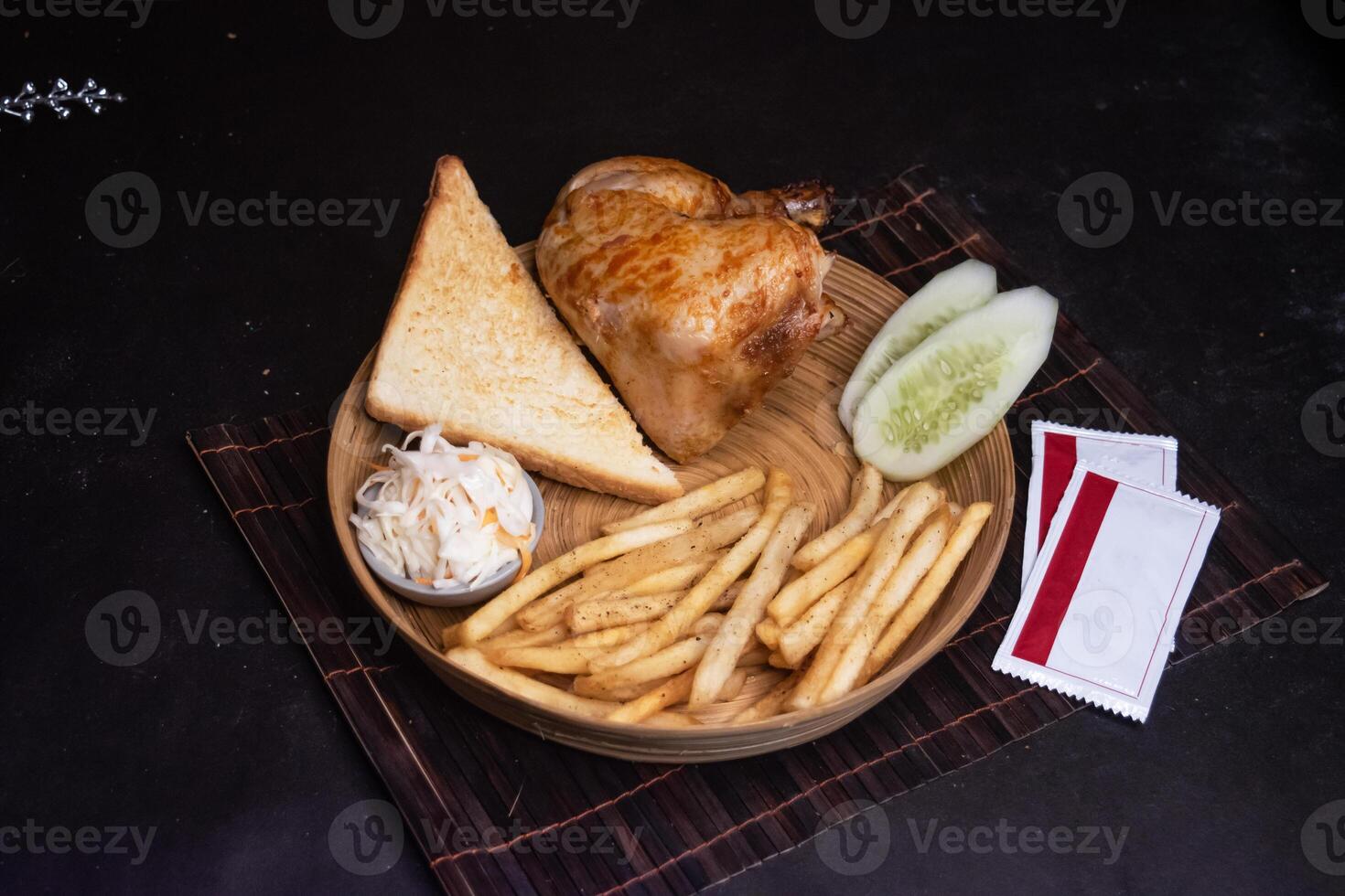 Grill Chicken with Toasted Bread, tomato, onion, lettuce leave, capsicum, french fries and salad served in wooden plate isolated on dark background side view of bangladeshi fast food photo