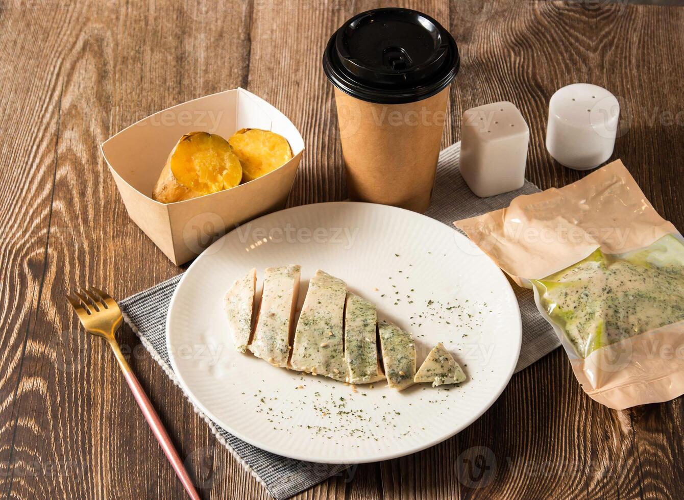 Pesto Basil Grilled Chicken breast Meal served in plate with roasted sweet potatoes, disposable cup of coffee and fork isolated on napkin side view of taiwan food on table photo