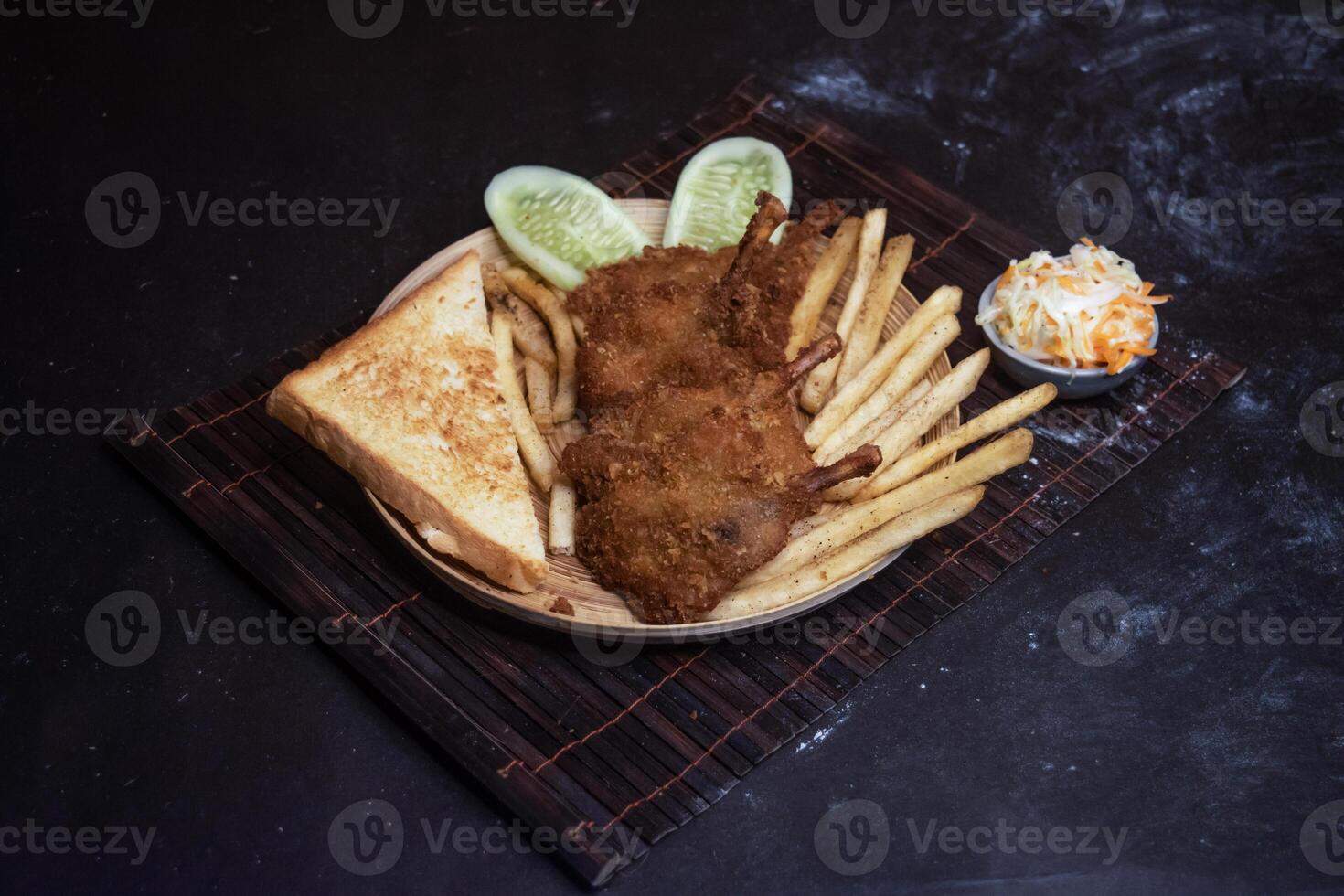 Chicken Wings with tomato, onion, lettuce leave, capsicum, french fries and salad served in wooden plate isolated on dark background side view of bangladeshi fast food photo